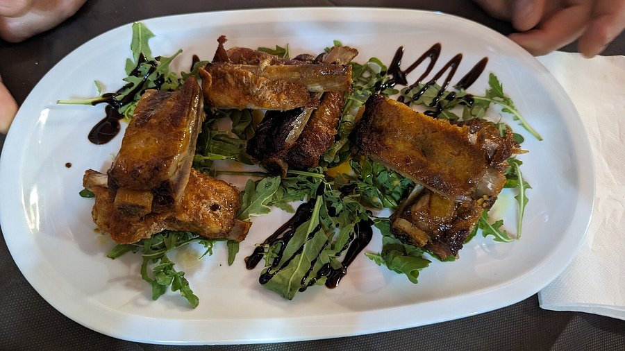 Costine di maiale dorate su rucola con glassa di aceto balsamico in un piatto ovale bianco della Trattoria Da Zia Lina