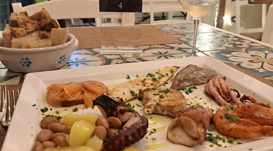 Antipasto di mare con polpo, fagioli, gamberi, salmone e pesce alla piastra su piatto bianco, Trattoria Da Zia Lina